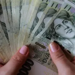 Dłonie trzymające stos banknotów 2000 koron czeskich. Czy to znak, które banki są zagrożone upadłością w Polsce?