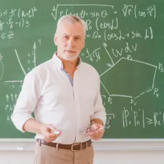Nauczyciel z tablicą pełną wzorów matematycznych, jakby potrzebował urlop dla poratowania zdrowia po długim semestrze.