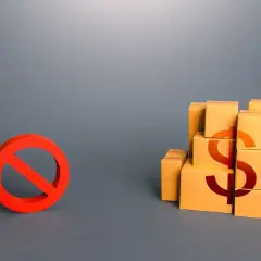 Czerwony znak zakazu obok stosu pudełek z symbolem dolara.