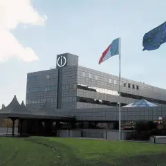 Siedziba Indesit, włoskiej firmy AGD. Flagi Włoch i UE powiewają przed nowoczesnym budynkiem.