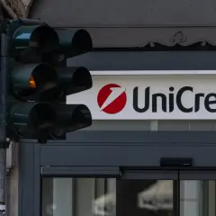 Czerwone światło dla pieszych i logo UniCredit. Czas na decyzję, kiedy wycofać się z funduszu inwestycyjnego.