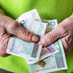 Dłonie trzymają polskie banknoty: 10, 20 i 100 zł. To może być wsparcie z tytułu renta socjalna.