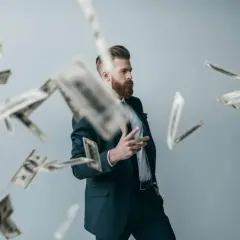 Mężczyzna w garniturze rzuca pieniędzmi, jakby świętował sukces swojego innowacyjnego patentu.