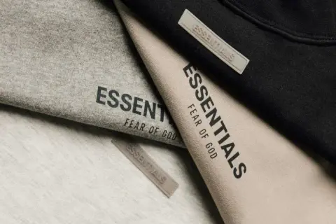 Ubrania marki Essentials, znanej z minimalistycznego stylu i jakości, w odcieniach szarości, beżu i czerni.