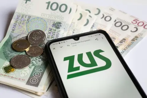 Złotówki i monety na ekranie telefonu z logo ZUS. Sprawdzanie emerytury pomostowej warunki.