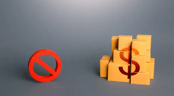 Czerwony znak zakazu obok stosu pudełek z symbolem dolara.