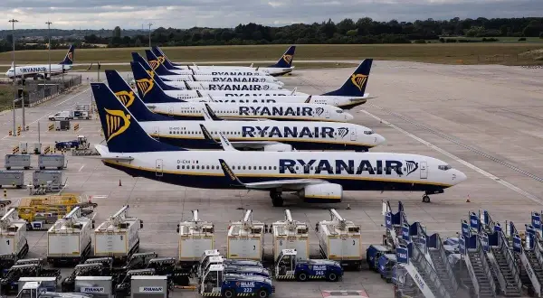 Samoloty Ryanair stojące w rzędzie na płycie lotniska. Taki widok może sugerować **overbooking** lub po prostu postój floty.
