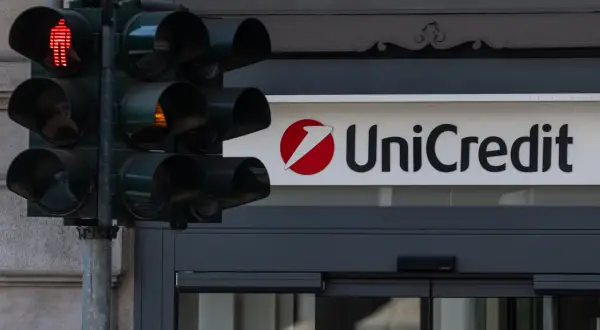 Czerwone światło dla pieszych i logo UniCredit. Czas na decyzję, kiedy wycofać się z funduszu inwestycyjnego.