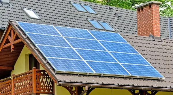 Panele fotowoltaiczne na dachu domu. Czy dofinansowanie do fotowoltaiki jest przychodem? Instalacja zbiera energię słoneczną.