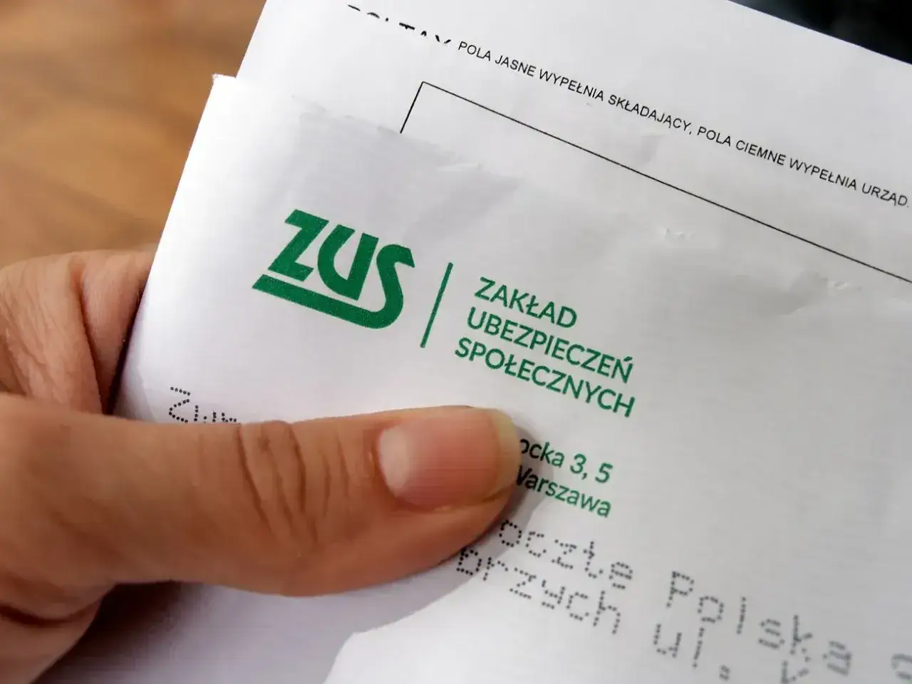 Dłoń trzyma dokument ZUS. To ważny krok w kierunku odprawy emerytalnej.