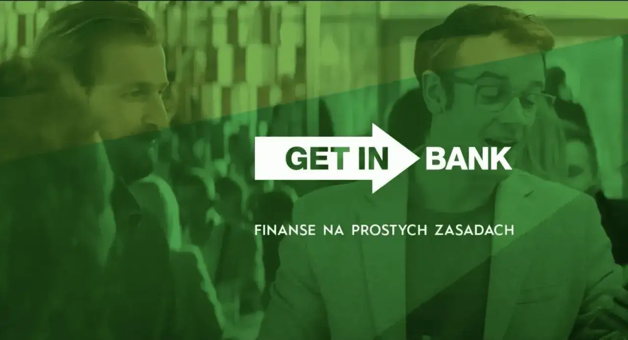 Mężczyźni rozmawiają, a na ekranie widnieje napis