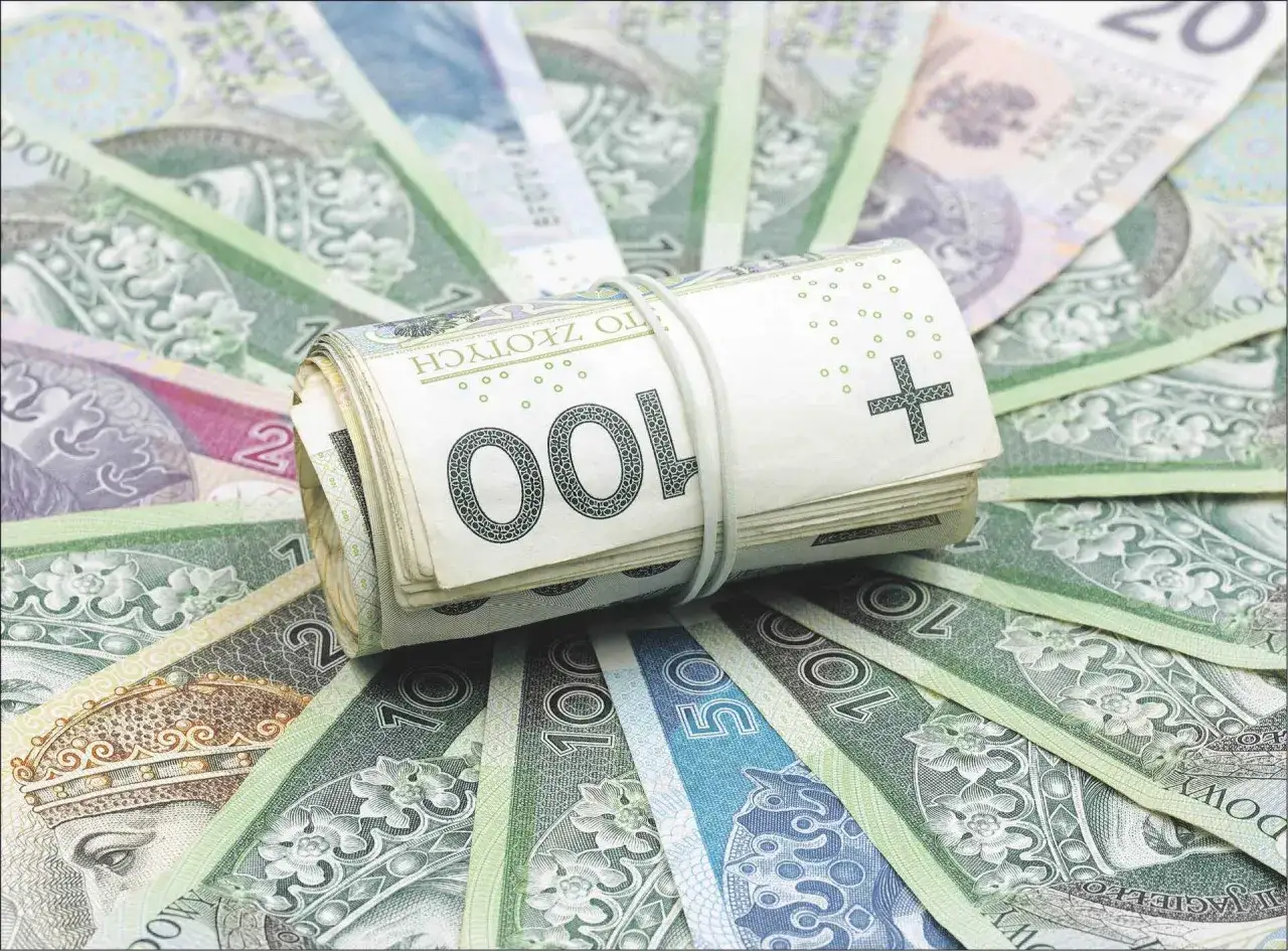 Zwijana sterta banknotów 100 zł na tle innych polskich pieniędzy. Czy to symbol obaw, które banki są zagrożone upadłością w Polsce?
