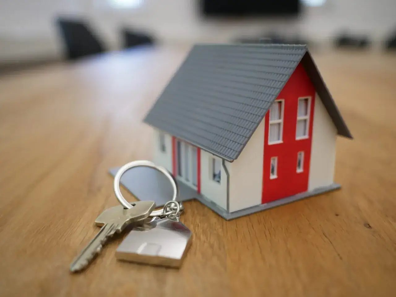 Klucze do domu i jego miniatura na drewnianym stole. Pytanie: jak zachować mieszkanie przy upadłości?